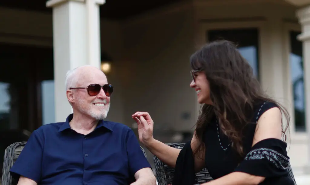 James M. Sweeney and co-author Rhonda Lauritzen sitting on a patio outside wearing sunglasses